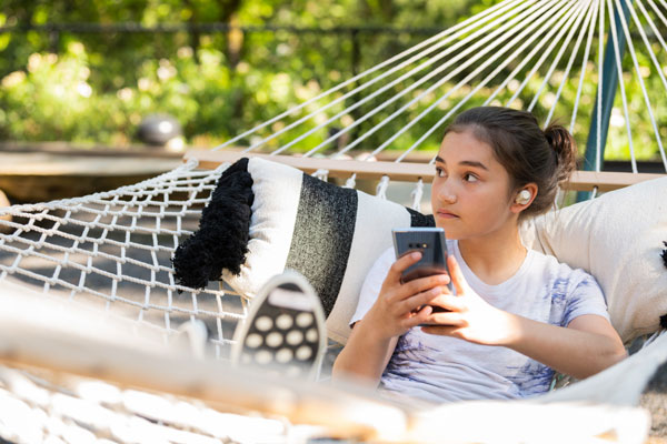 Girl in hammock listening to wireless headphones